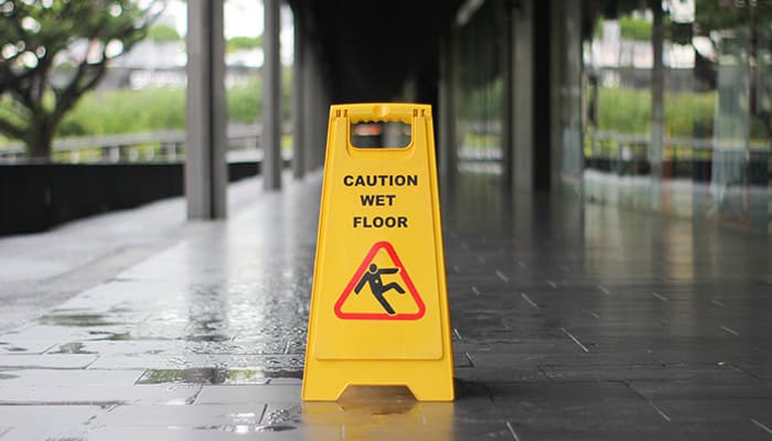 A caution wet floor sign on stood on a wet floor surface